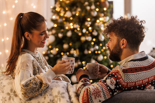 istock Young couple smiling at each other while relaxing and enjoying hot chocolates 1498120159
