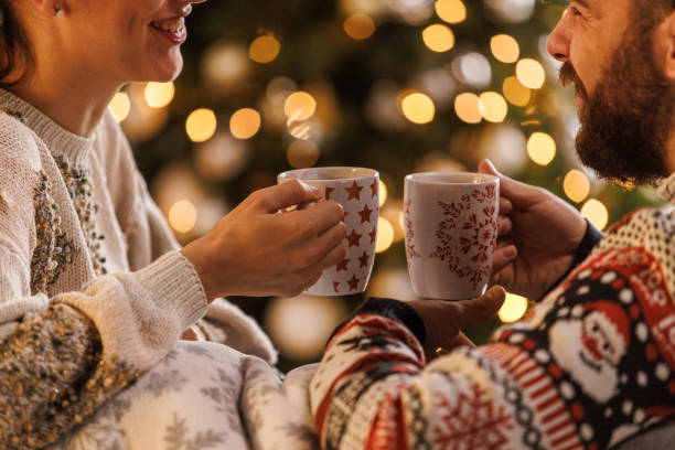 Young couple smiling at each other while relaxing and enjoying hot chocolates