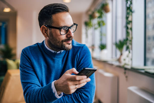 istock Side view of a businessman, using a mobile phone while sitting at the office. 1498121770