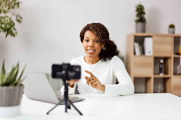 istock Happy African woman using a smartphone on a tripod while recording video for her social networks. 1498126862