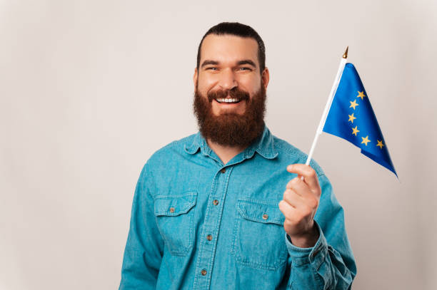 Wide smiling man is waving the European Union flag over white background. stock photo