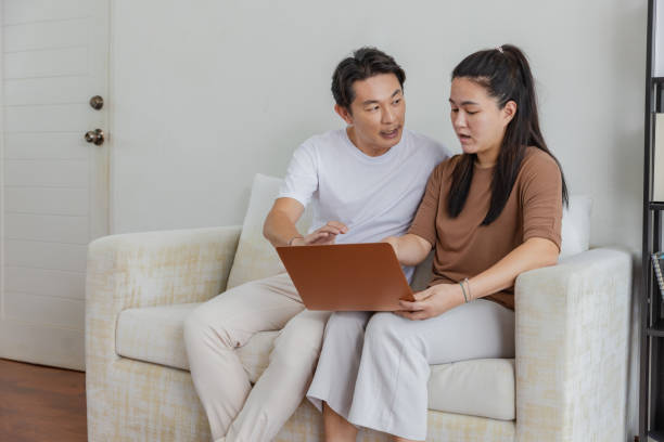 istock Couple talking and looking at computer together at home. 1498129047