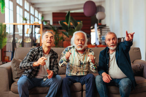 istock Senior men watching game together on couch. 1498129246