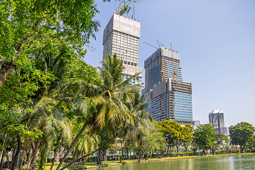 Lumphini Park, Bangkok, Thailand - March 27th 2023: View to the skyline of the modern Bangkok over a lake in the large public park in the center of the capital of Thailand
