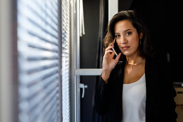 istock Charming young brunette smiling at camera while talking on the phone 1498129768