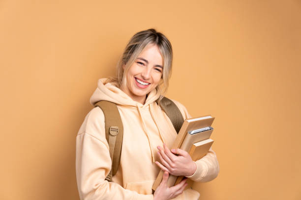istock student holding academy book and smiling in beige colors 1498129946
