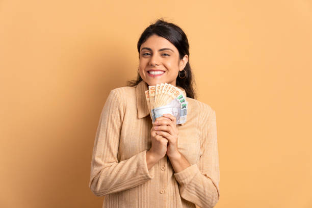 mulher mostrando dinheiro, moeda brasileira - bill looking cheerful latin american and hispanic ethnicity - fotografias e filmes do acervo