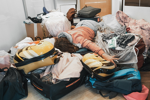 Difficult family travel preparation. Moving, packing unpacking of lot of things,clothes, suitcases, baggage at home in apartment. Many packages,bags.Mess,disorder.Gathering for vacation trip journey.