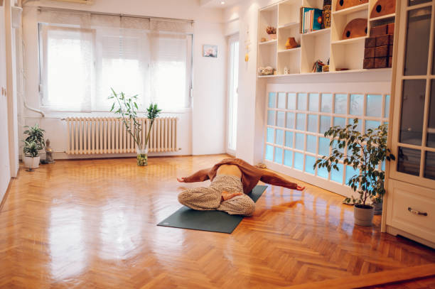 istock Girl lying on a mat and bending backwards while stretching in a cozy studio. 1498139696