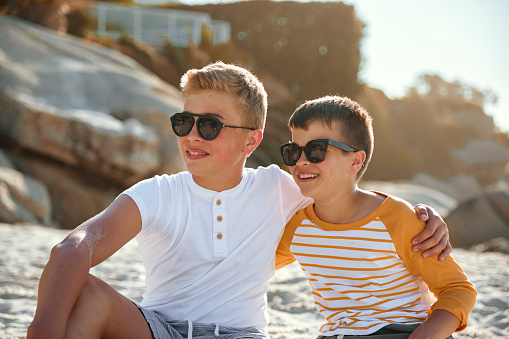 Shot of two adorable brothers sitting at the beach