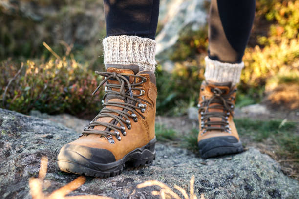 Hiking boot and alpaca sock. Legs with ankle boots on mountain trekking trail