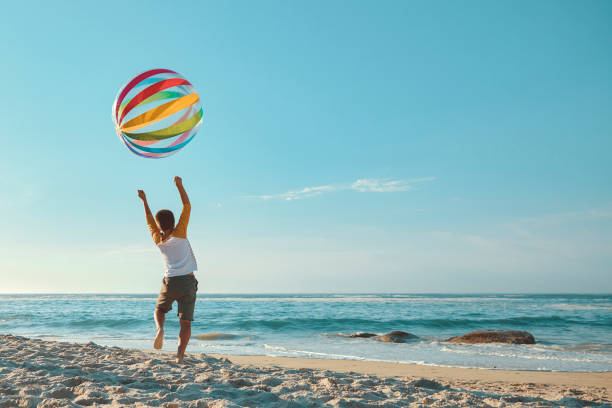 Young boy playing with a ball at the beach during summer
