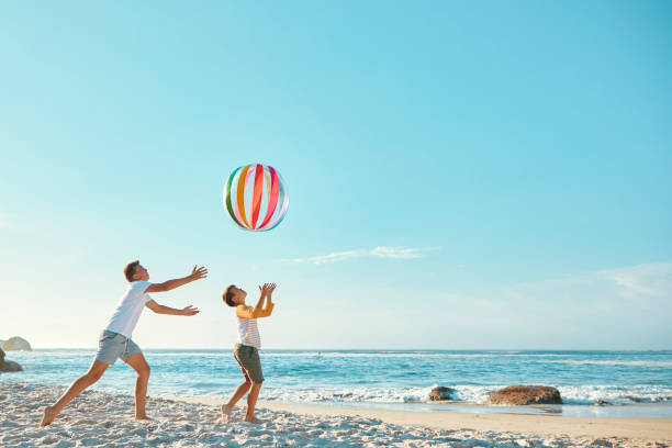 Brothers playing with a ball at the beach Two brothers playing with a ball at the beach during summer blue brothers stock pictures, royalty-free photos & images