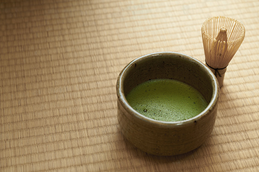 Green matcha tea powder in cups with traditional iron kettle.