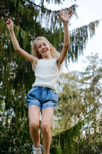 A happy teenager in blue shorts and a white T-shirt bouncing around in a green forest