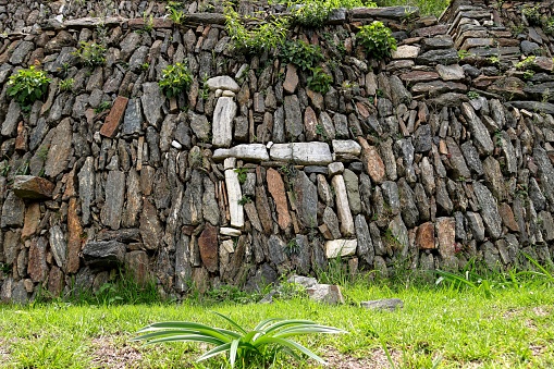 An old stone wall in front of a lush, green landscape in the Andes mountains