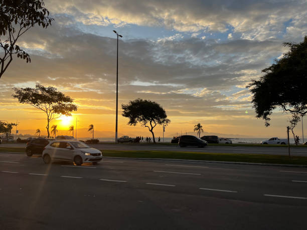 Florianópolis, Santa Catarina - Brazil - May 22, 2023: View of the sunset at the avenue 'Beira Mar Norte', along with people, cars and nature in Florianópolis, Santa Catarina state - Brazil