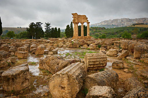 Ruins of Temple of Castor and Pollux with Agrigento in the background on a rainy day.