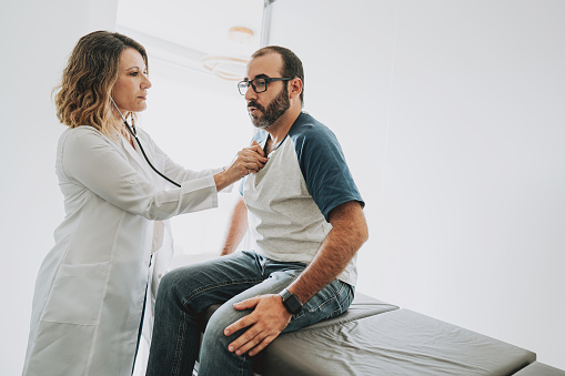 Portrait of a female doctor listening to a patient's heartbeat