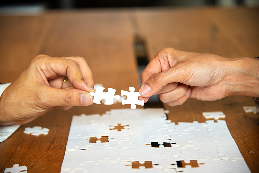 Hand of businesspeople holding the piece of Jigsaw Puzzle to connecting