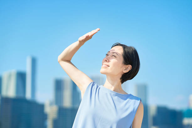 A woman blocking the strong sunlight under the blue sky on fine day