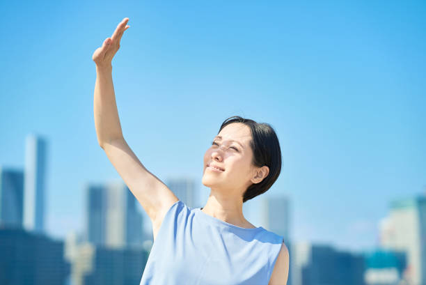 青空の下で強い日差しを遮る女性 - 暑さに弱い 日本人 ストックフォトと画像