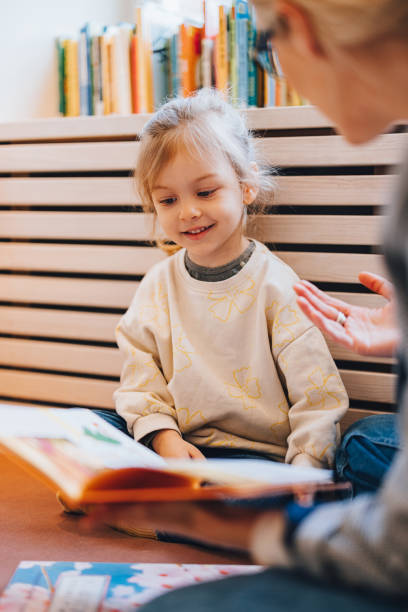 portret uroczej dziewczynki siedzącej na podłodze i patrzącej na książkę - law library school education zdjęcia i obrazy z banku zdjęć