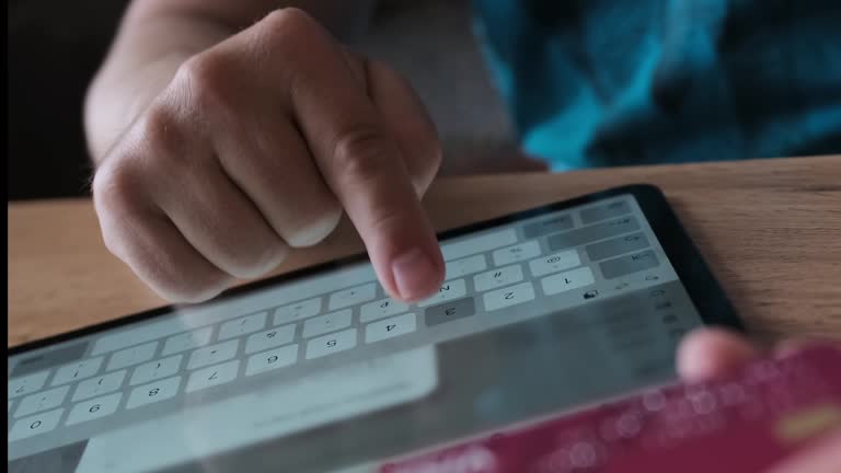 Man hand enters personal data on tablet screen holding bank card