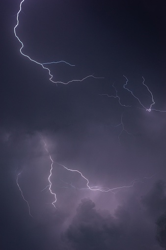 A dramatic and powerful purple lightning bolt illuminating a dark night sky