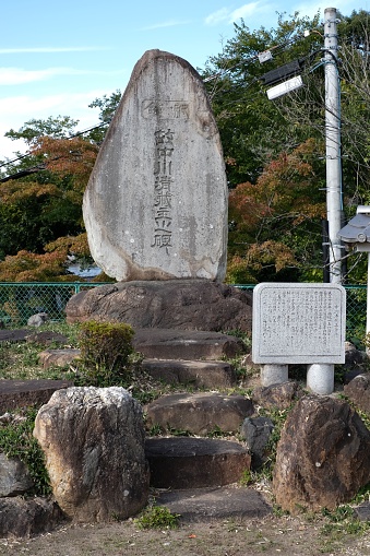 Inuyama, Japan – February 01, 2023: An idyllic oriental garden featuring steps, vibrant trees, and a tall stone sign in Inuyama, Japan