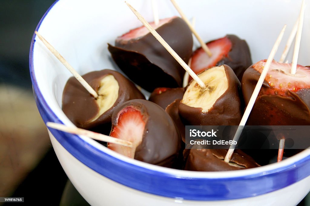 Delicious chocolate covered strawberries and banana Delicious chocolate covered strawberry and banana dessert in blue and white ceramic bowl. Banana Stock Photo