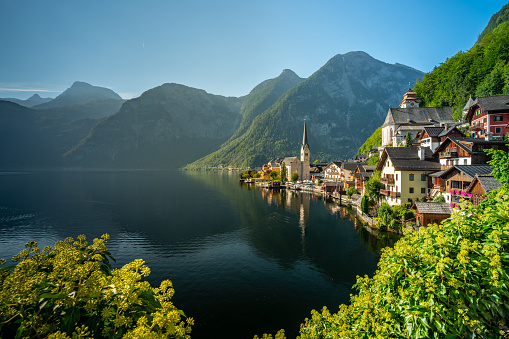 sunny morning at Hallstatt lake with beautiful alpine houses of town nestled between mountains and water