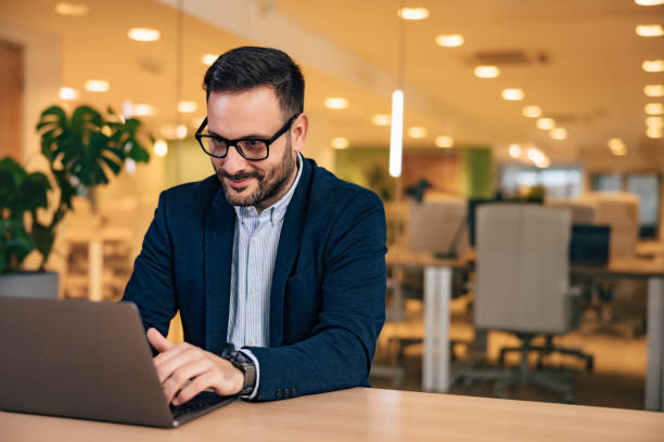 istock Smiling businessman typing on a laptop, sitting at the office, elegantly dressed. 1498171071
