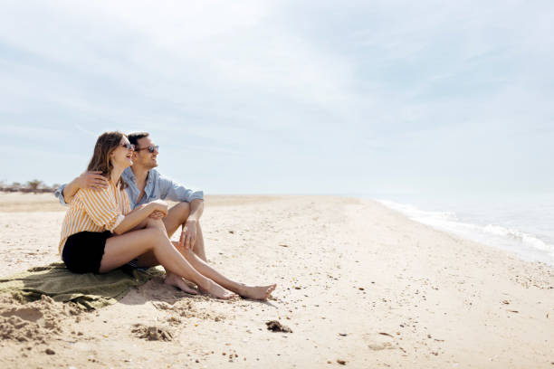 istock Couple sitting on a beach and looking at a view 1498172149
