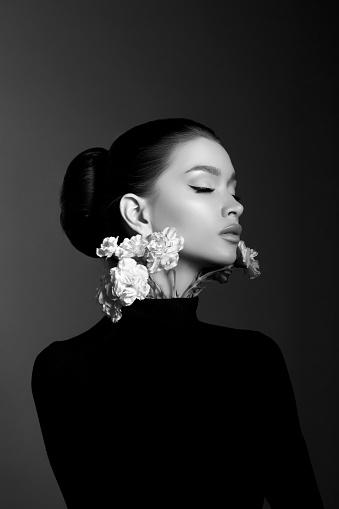 Perfect art woman in black turtleneck on a dark background. Brunette long hair is pulled into a bun. Evening makeup