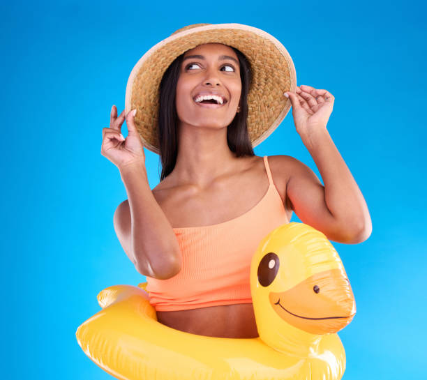 istock Thinking, hat and rubber duck with a woman on a blue background in studio ready for summer swimming. Happy, travel and vacation with an attractive young female looking excited to relax or swim 1498172517