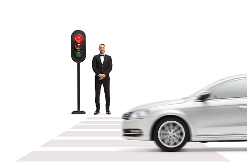 Man in a black suit with bow tie waiting at traffic lights isolated on a white background