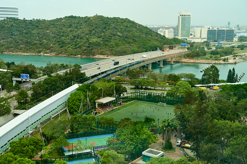 Aerial view of Man Tung Road Park with tennis and soccer fields. In the background the North Lantau Highway. Tung Chung. Islands District. Lantau Island. Hong Kong.