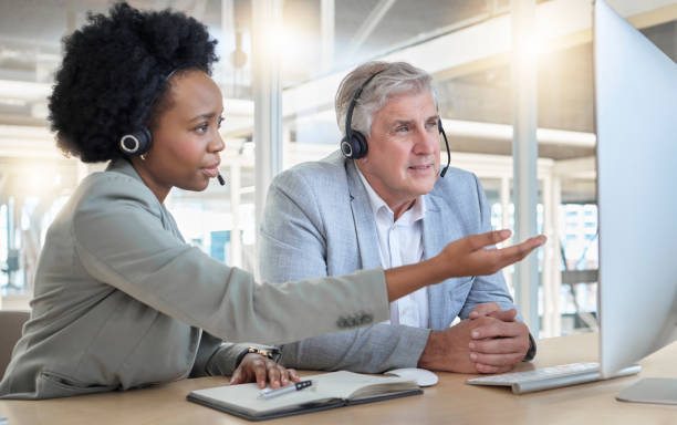 istock Call center, teamwork and coaching, black woman with man at computer at help desk office. Customer service consultant manager, support and training at advisory agency with diversity and trust in team 1498176770