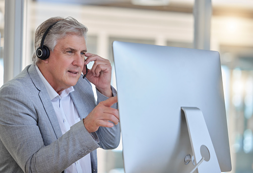 Call center, advice and senior man at computer with headset in consulting in customer service office . Ceo, insurance sales and mature businessman at advisory agency, contact us and crm networking.