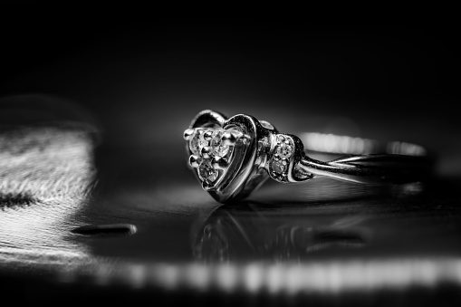 A gold ring with a heart-shaped gemstone set into it on a black background