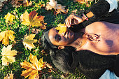 Young adult black woman lying down in yellow autumn leaves