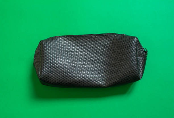 Black pencil case isolated on green background. Top view, flat lay.