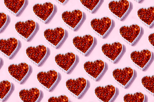 Omega 3 Fish Oil Capsules  In A Heart-Shaped Plate on Pink Background.