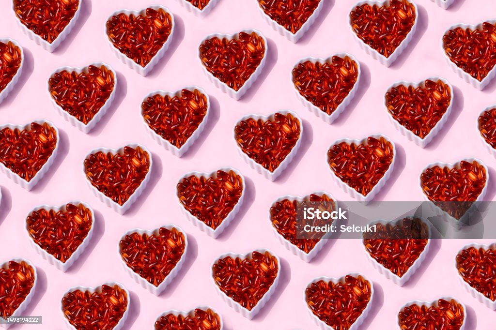 Omega 3 Fish Oil Capsules  In A Heart-Shaped Plate on Pink Background. Fish Oil Stock Photo