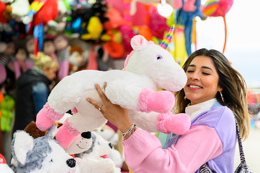 Happy woman holding a cuddly toy she has won at the fair