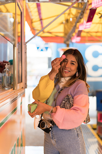 Woman showing a fairground coin at the ticket booth of an amusement ride.