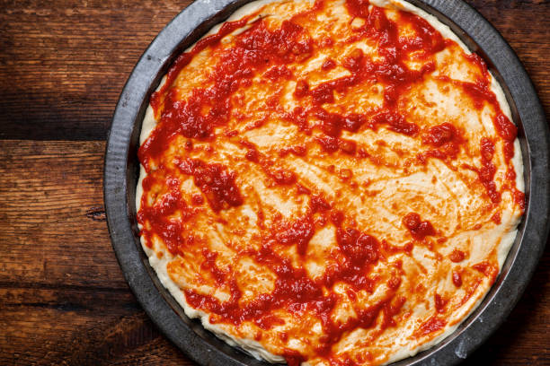 istock pizza cooking. Dough smeared with tomato sauce. 1498197465