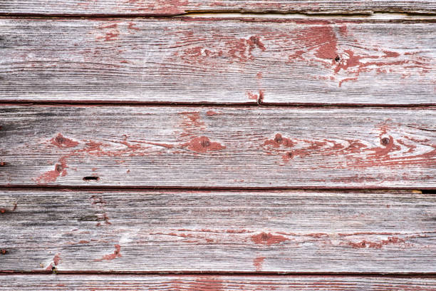 Image shows weathered, gray, vertical wood planks with faded black paint markings. Wood grain is visible, along with knots and nails.