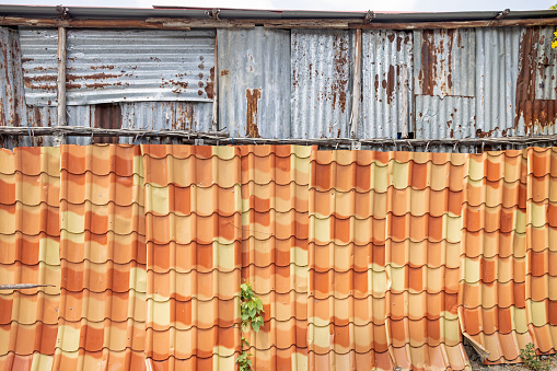 Fence made of a old tin roof and a house clad  in corrugated iron in the center of the Thai capital